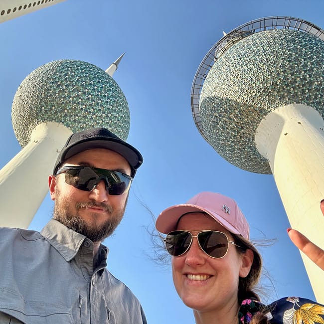 Desert horizons motorcycle expedition, kuwait: smiling couple poses in front of kuwait’s globe-like mosque towers