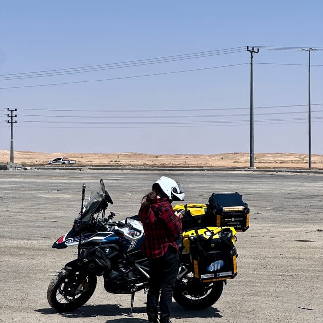 Desert horizons motorcycle expedition in saudi arabia: two adventure motorcycles parked on a desert road with riders adjusting gear