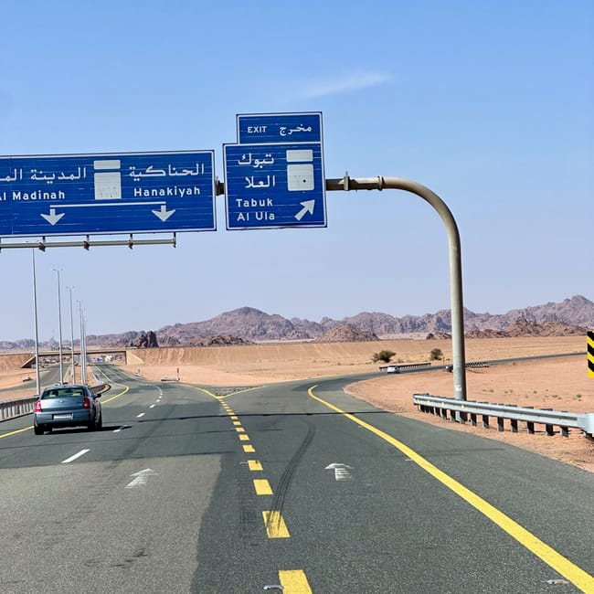Skrzyżowanie dróg w al ula z tablicami na tabuk i al madinah na tle pustynnych gór