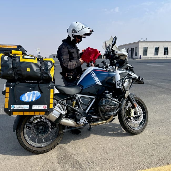 Motocyklista przy załadowanym bmw gs na pustyni w arabii saudyjskiej