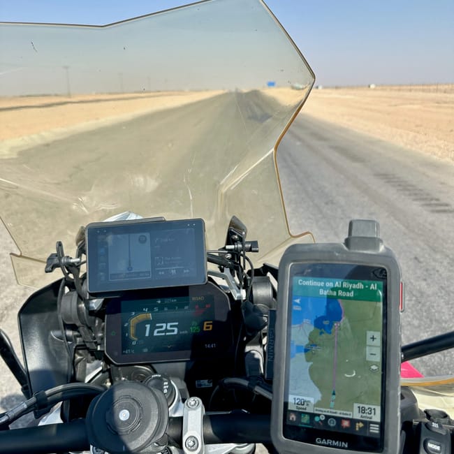 Motocykl na pustynnej drodze w arabii saudyjskiej, z nawigacją pokazującą trasę do al riyadh–al batha road.