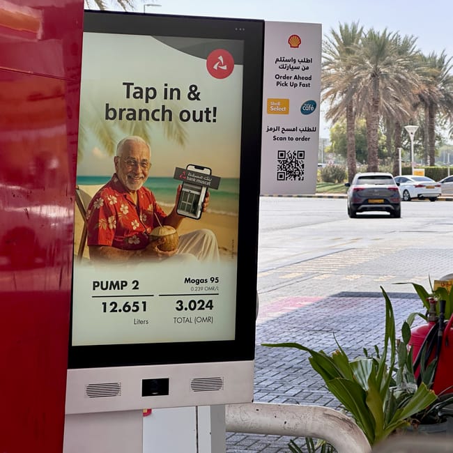 Stacja paliw shell w muskacie z wyświetlaczem promocji i palmami w tle
