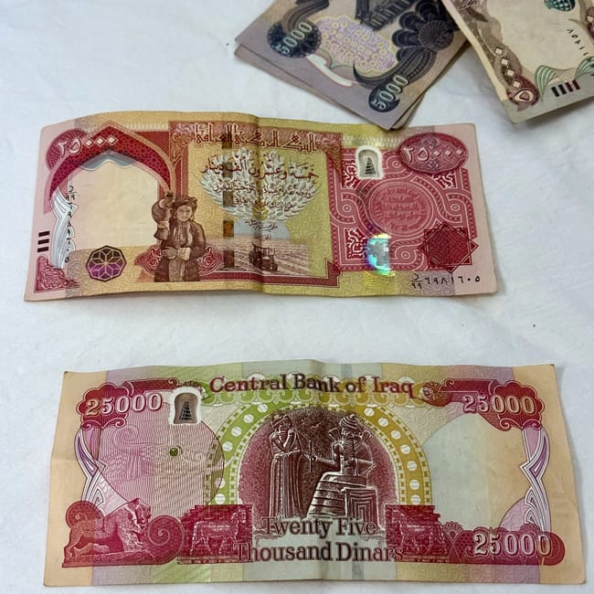 Banknoty irackie o nominale 25 000 dinarów na białym tle