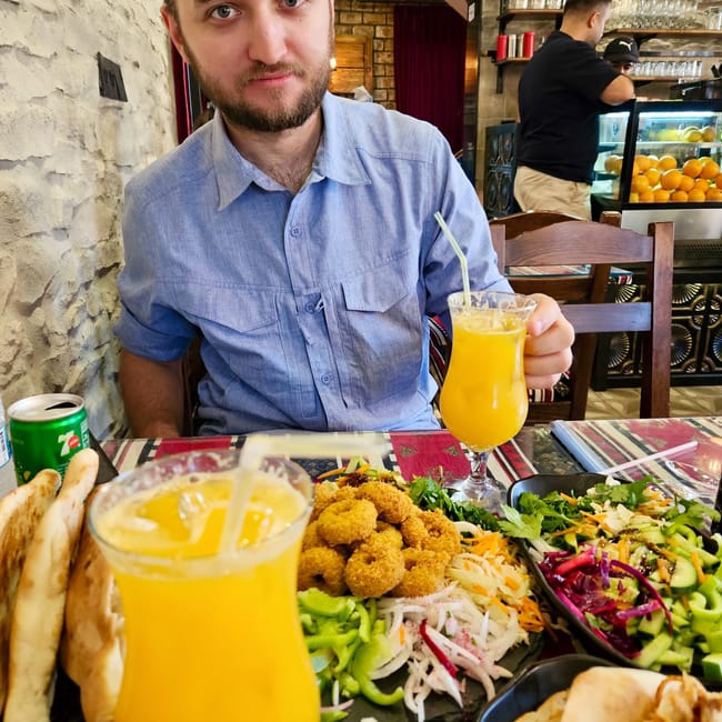 Restauracja erbil foods w iraku z daniami, sokiem i siedzącym przy stole mężczyzną