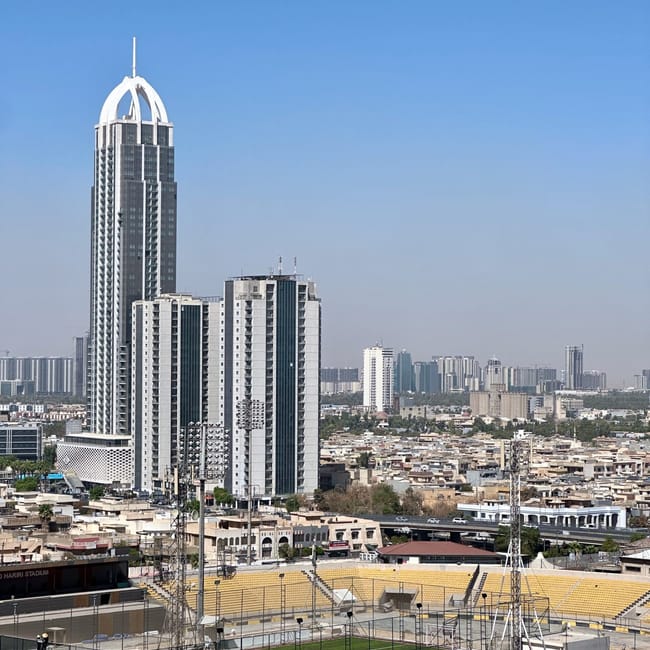 Widok na erbil z hotelu: wieżowce, stadion i zabudowa miasta pod bezchmurnym niebem.