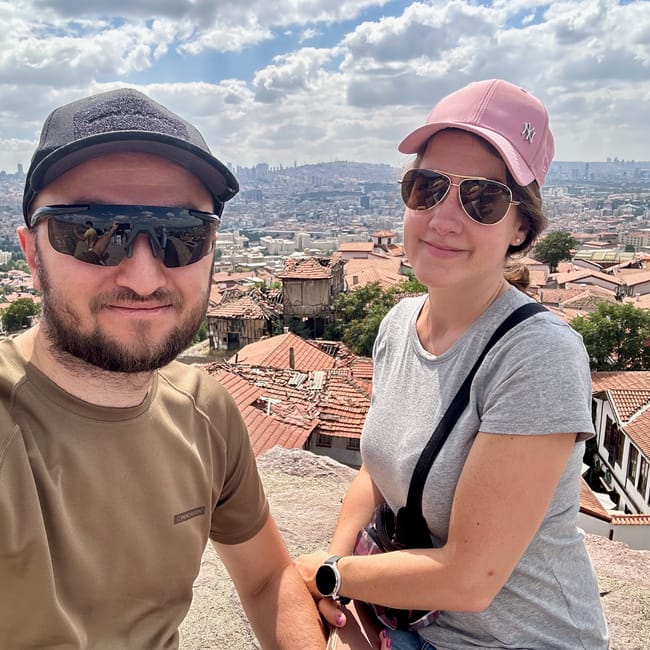 Tourists posing in ankara, turkey, near a castle overlook with a city skyline behind them