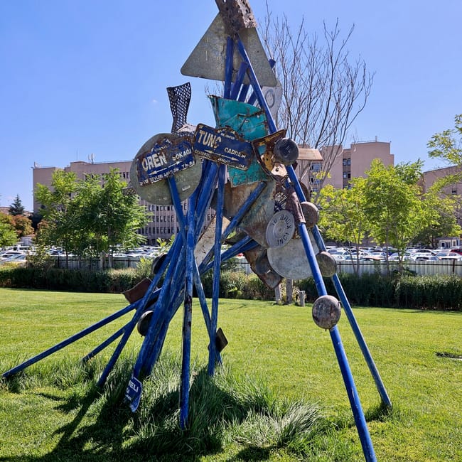 Metal sculpture in ankara cso ada, turkey, with blue and rusted circular plates outdoors on a lawn