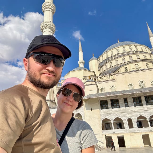 Couple posing at turkey’s ankara kocatepe mosque with minarets and domes under a blue sky