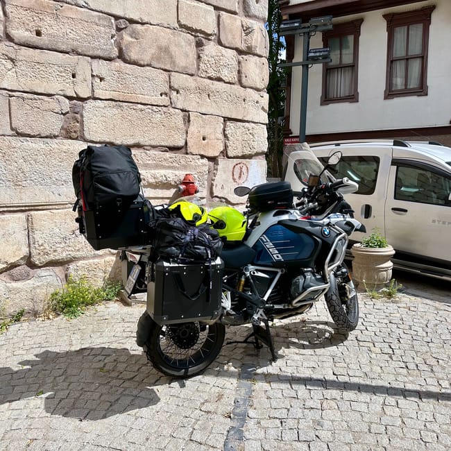 Motocykl turystyczny zaparkowany na brukowanej ulicy w ankarze, obok kamiennego muru.
