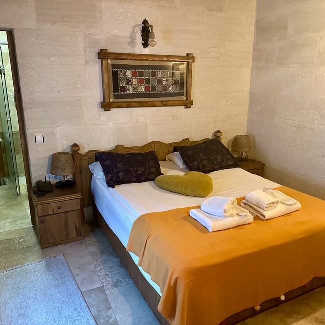 Pokój w goreme accommodation w turcji z łóżkiem, ręcznikami i łazienką w tle