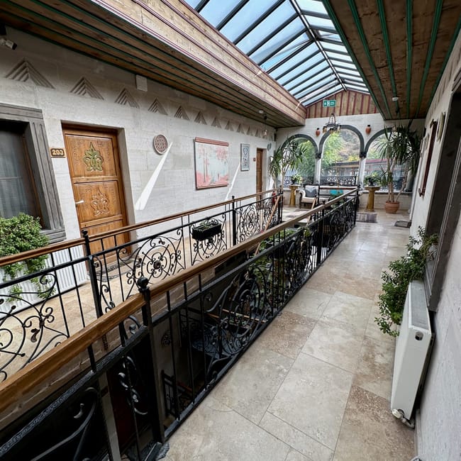 Korytarz w obiekcie noclegowym goreme accomodation w turcji z przeszklonym dachem i dekoracyjnymi balustradami