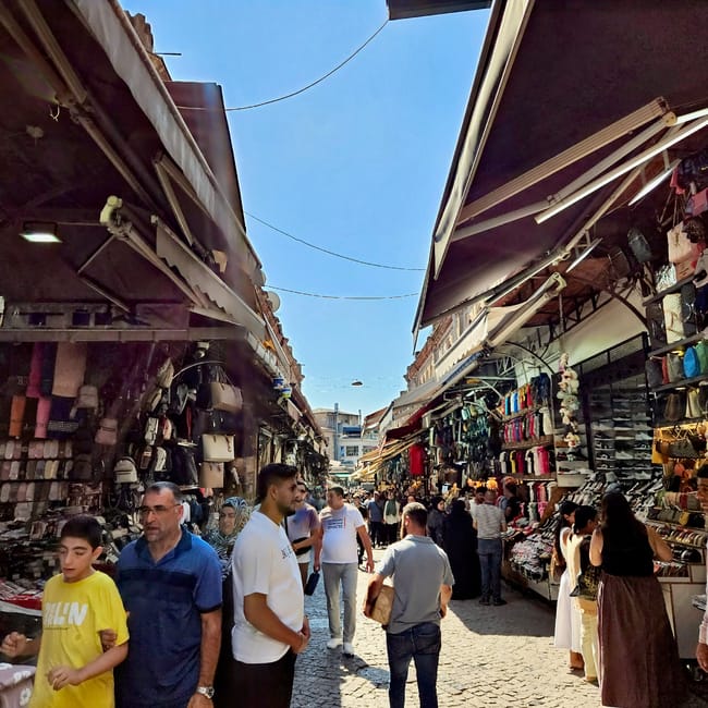 Grand bazaar w stambule z tłumem w wąskiej uliczce między straganami z odzieżą i pamiątkami