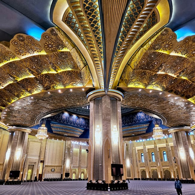 Kuwait city grand mosque interior with ornate arches, gold patterns, and blue-lit ceiling details
