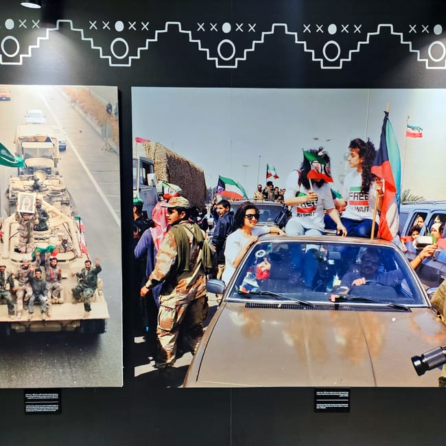 Visitors view kuwait city national museum display photos of armed vehicles and crowds with flags