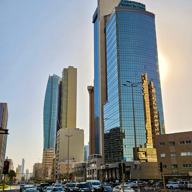 Kuwait city street view with modern office towers and a glass skyscraper in the foreground