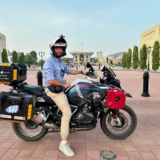 Mężczyzna na motocyklu podróżnym przed pałacem al alam w maskacie w omanie.