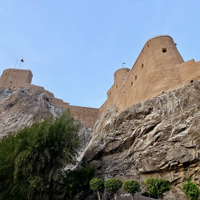 Fort muscat forties w omanie na skalistym wzgórzu, z wysokimi murami i wieżami na tle błękitnego nieba