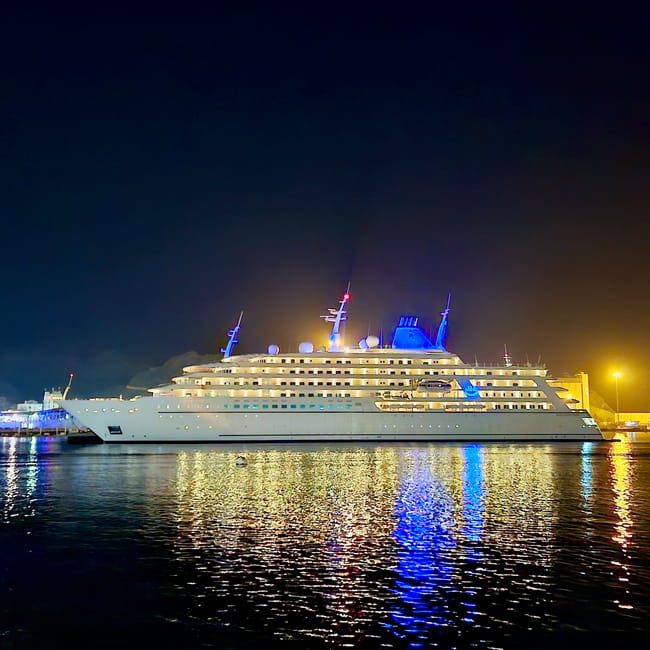 Nocny widok na muscat muttrah corniche w omanie z oświetlonym statkiem wycieczkowym odbijającym się w wodzie