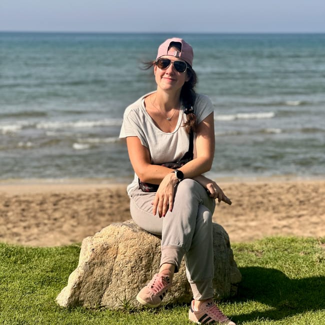 Kobieta siedząca na kamieniu przy plaży qurum w muskacie, na tle morza i piaszczystego brzegu