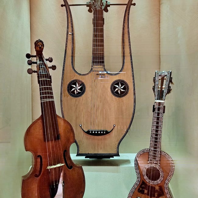 Ekspozycja instrumentów strunowych w muscat royal opera house w omanie, z dużą lirą pośrodku.