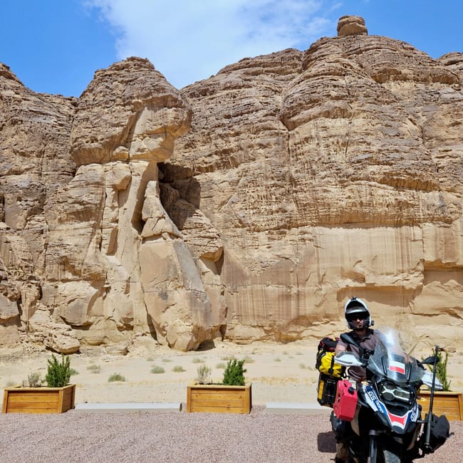 Motorcyclist in front of al ula caravans by habitas at saudi arabia, with rocky desert cliffs and blue sky