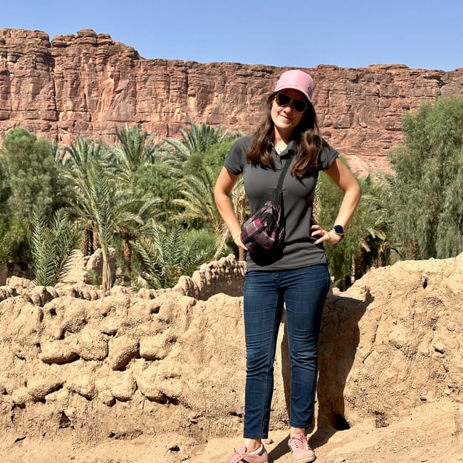 Woman with sunglasses and pink cap posing by al ula oasis near old town in saudi arabia