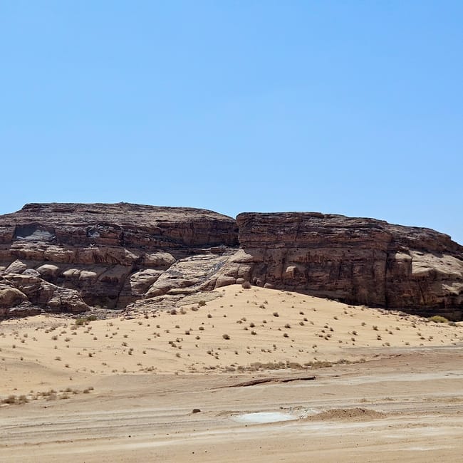 Al ula, saudi arabia desert valley with sandy dunes and rocky cliffs under a clear blue sky