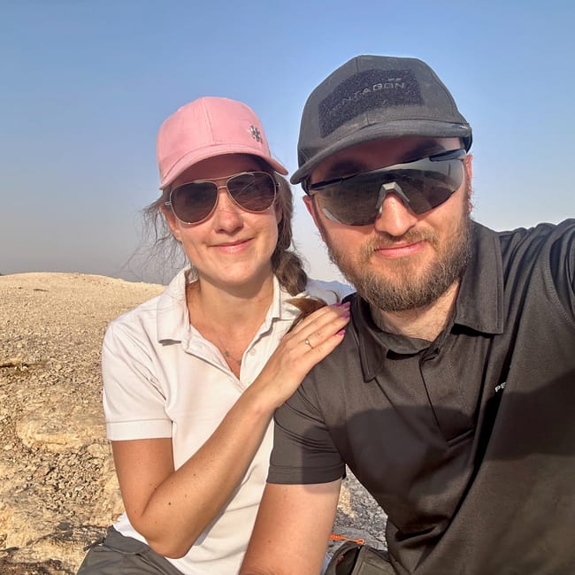 Couple taking a selfie at the edge of the world, saudi arabia, wearing caps and sunglasses in a desert landscape