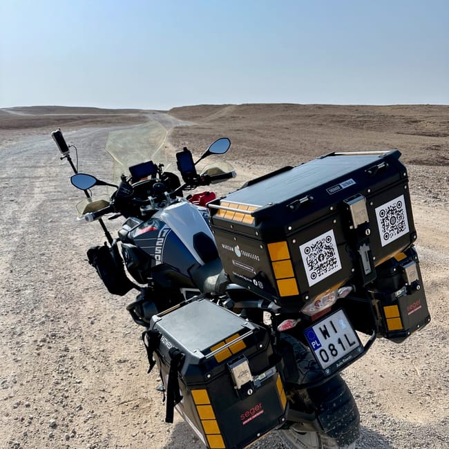 Motorcycle with mounted luggage at edge of the world in saudi arabia, on a rocky desert road