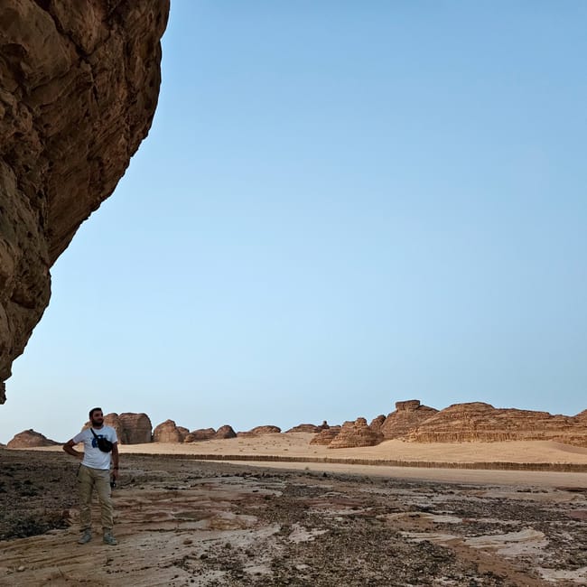 Man standing in al ula elephant rock desert landscape in saudi arabia under a clear blue sky