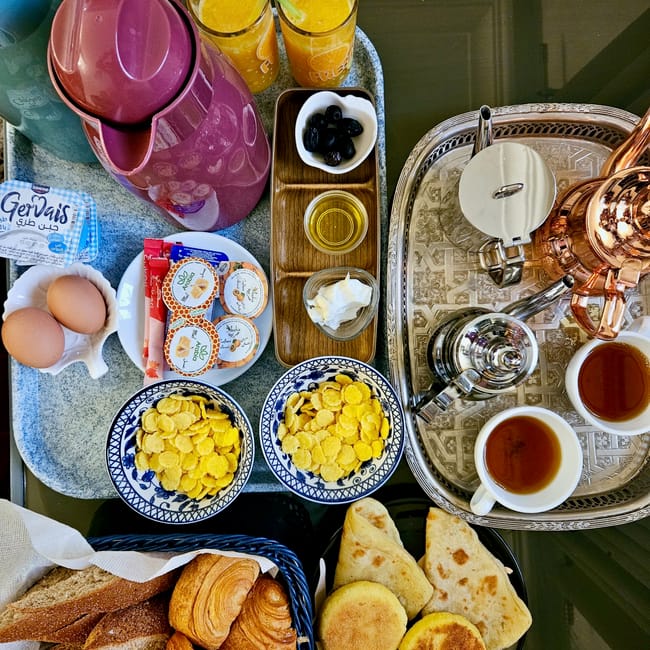 Morocco, marrakech foods breakfast spread with mint tea, bowls of eggs and olives, and assorted breads and pastries