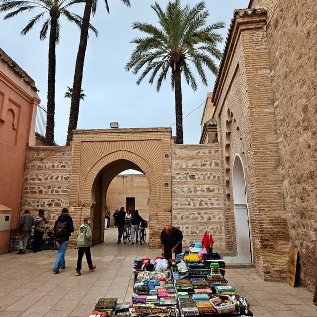 Koutoubia mosque in marrakesh, morocco, with tall palm trees and a street market stall in the foreground