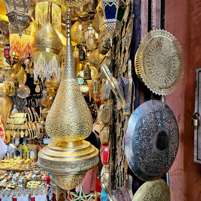 Souk semmarine in marrakesz, morocco, with ornate brass lanterns and perforated metal trays hanging on display