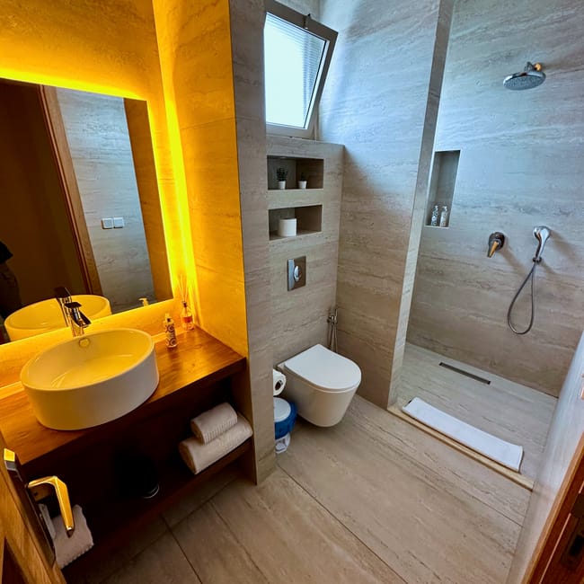 Essaouira hotel, nasz nocleg: nowoczesna łazienka z umywalką, toaletą i prysznicem, ciepłe żółte światło