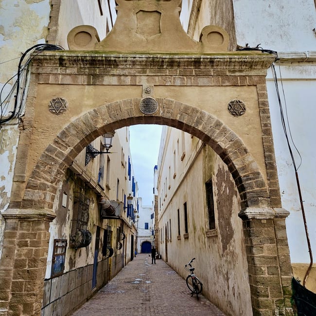 Brama w medynie essaouira w maroku z ozdobnym łukiem i ozdobami na tle wąskiej uliczki