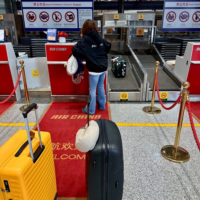 Stanowisko odprawy air china na lotnisku w pekinie, z pasażerką i walizkami przy stanowisku check-in