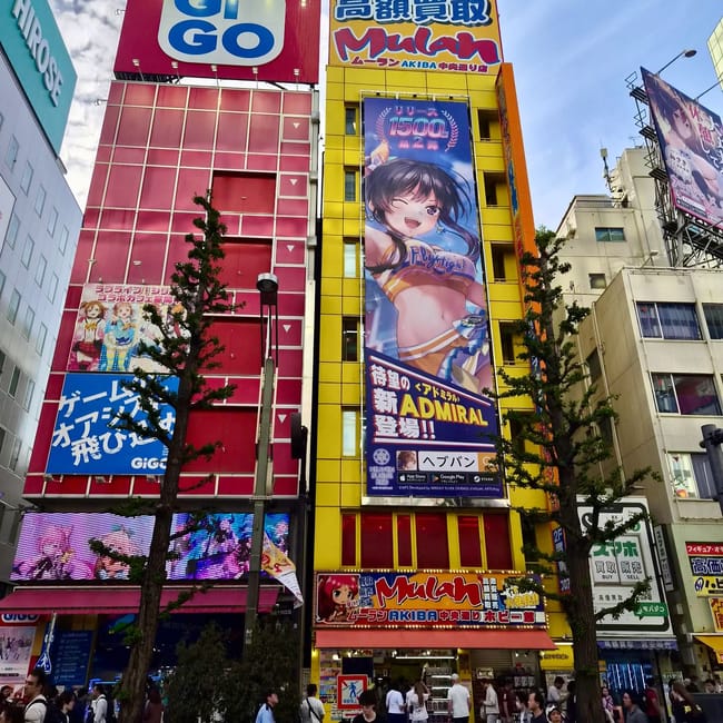 Akihabara w tokio z kolorowymi reklamami sklepów gigo i mulan oraz tłumem przechodniów