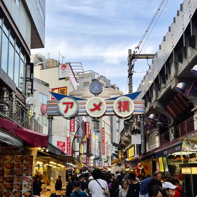 Wejście do ameyoko market w tokio z tłumem przechodniów i straganami po obu stronach ulicy