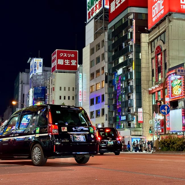 Kabukicho w tokio nocą, z taksówkami i neonowymi reklamami w dzielnicy rozrywki
