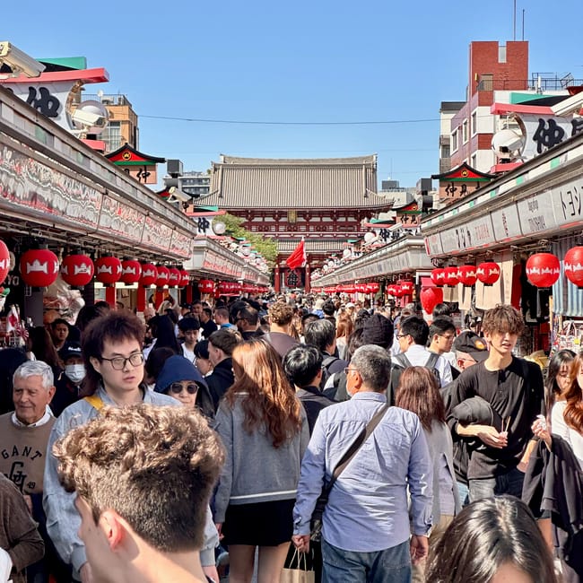 Nakamise w tokio pełna tłumu turystów, z czerwonymi latarniami i świątynią w oddali