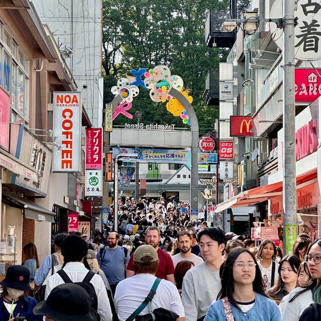 Takeshita street w tokio, zatłoczona przez tłum spacerujących ludzi przy sklepach i neonach