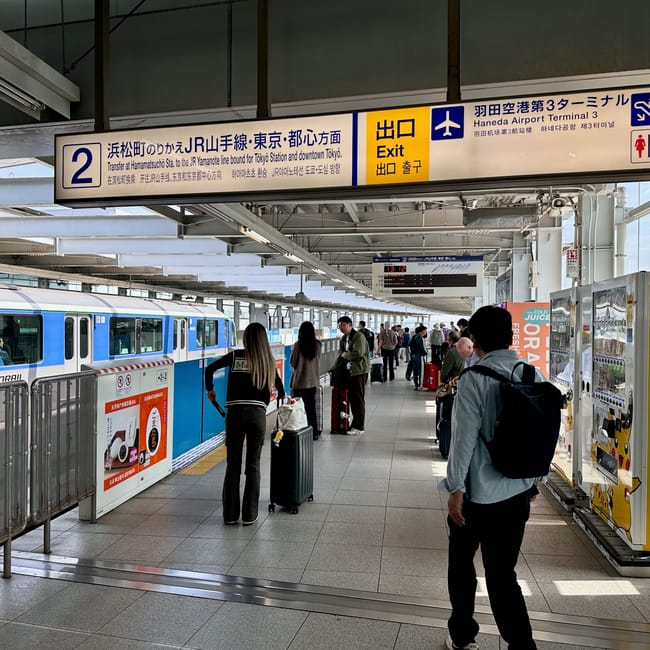 Stacja kolejki monorail w tokio, peron z pasażerami i oznaczeniami przejścia na jr yamanote oraz haneda airport terminal 3