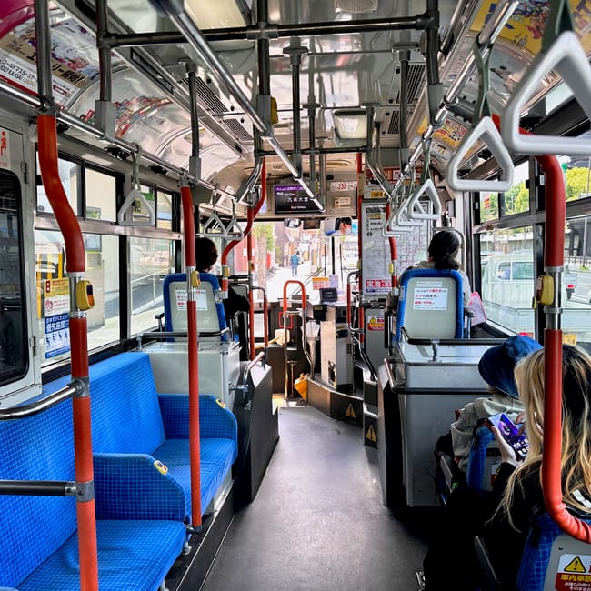 Wnętrze autobusu w kioto z pasażerami i widokiem na ulicę na zewnątrz