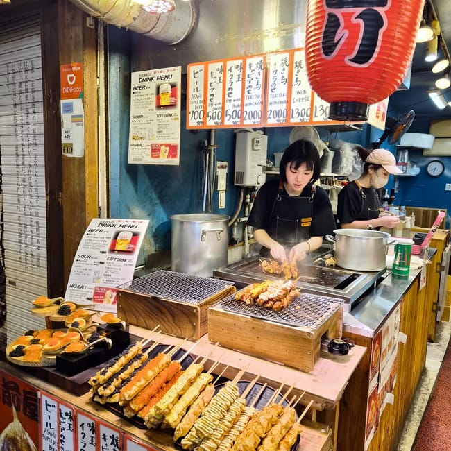 Stoisko z jedzeniem na nishiki market w kioto, z grillowanymi szaszłykami i menu