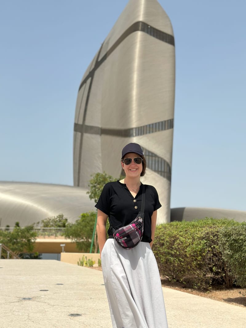 Jadzia in saudi arabia standing in front of a modern tower under a clear sky