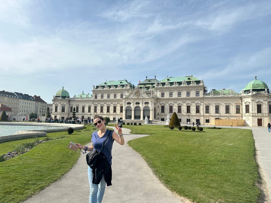 Pałac belweder w wiedniu z ogrodem i fontanną, a na pierwszym planie uśmiechnięta turystka.