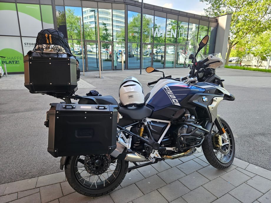 Motocykl bmw z kuframi zaparkowany przy nowoczesnym budynku w bratysławie.