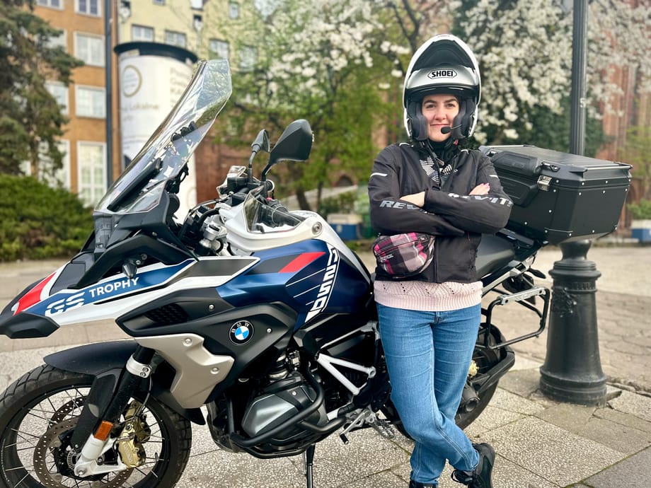 Kobieta w kasku stoi przy motocyklu bmw gs trophy w gdańsku.