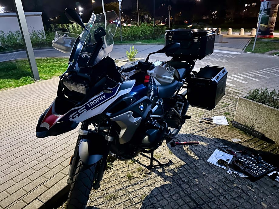 Bmw r1250gs trophy z kuframi zaparkowany nocą na chodniku.