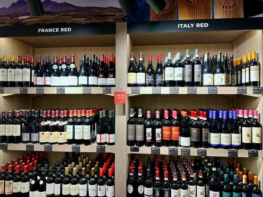 Półki z czerwonym winem w sklepie, z oznaczeniami france red i italy red.